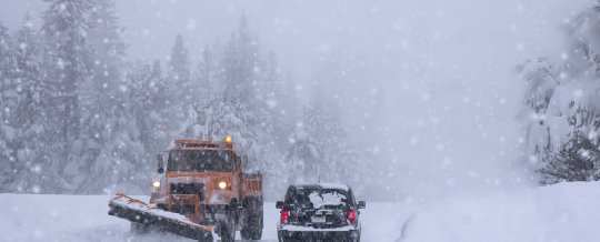 Snow plow and car on snowy road