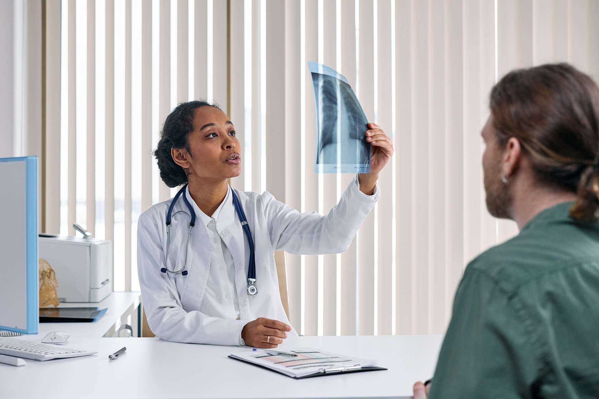 Woman Doctor Holding Xray Film In Front Of Patient