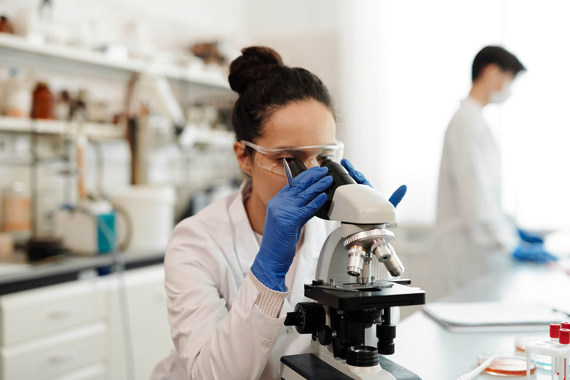 Woman Scientist Looking Through Microscope In Lab